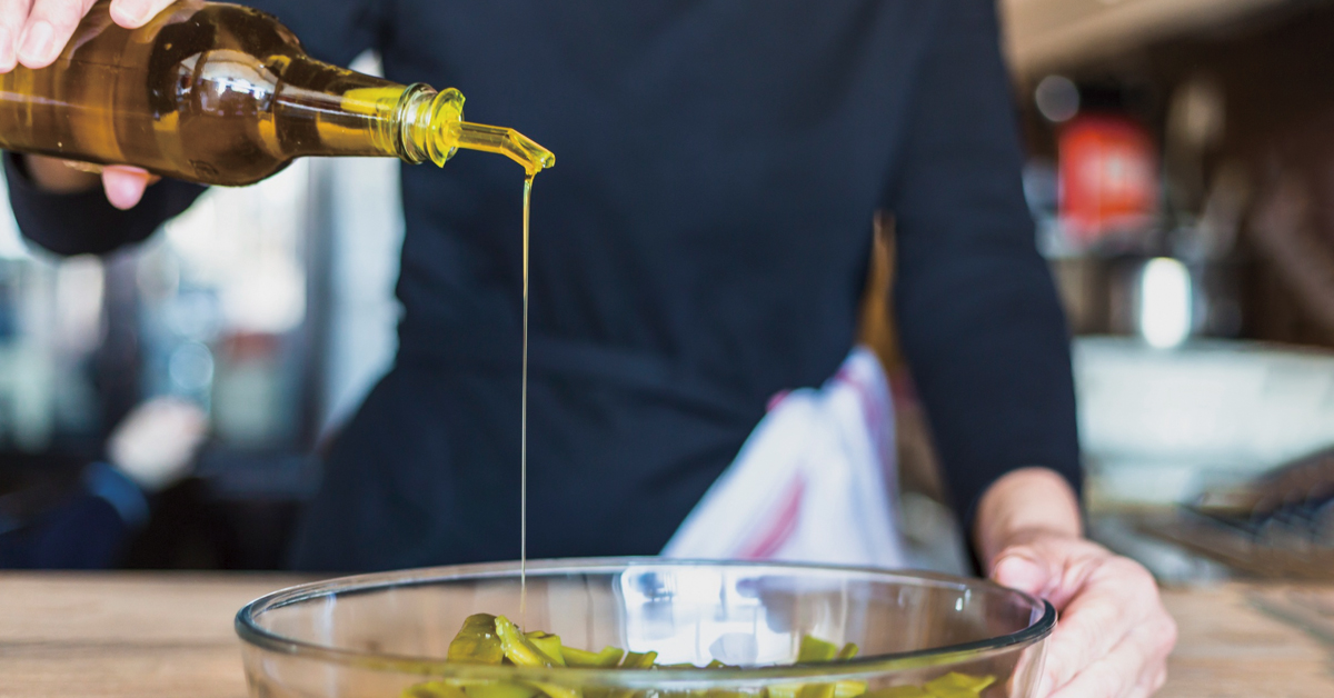 mujer virtiendo aceite de oliva en una ensalada