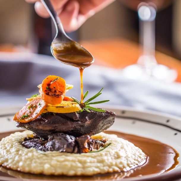 chef pouring sauce over meat